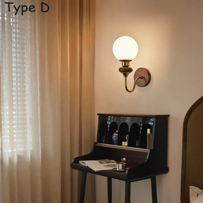 A simple wall sconce with a wood base and a spherical glass shade attached to a brass arm.