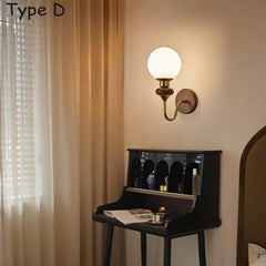 A simple wall sconce with a wood base and a spherical glass shade attached to a brass arm.
