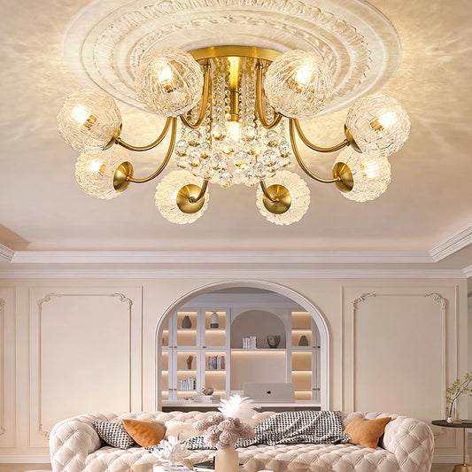 A polished gold semi-flush ceiling light with multiple ripple glass globes and crystal accents, illuminating a living room with an arched doorway and a sofa.