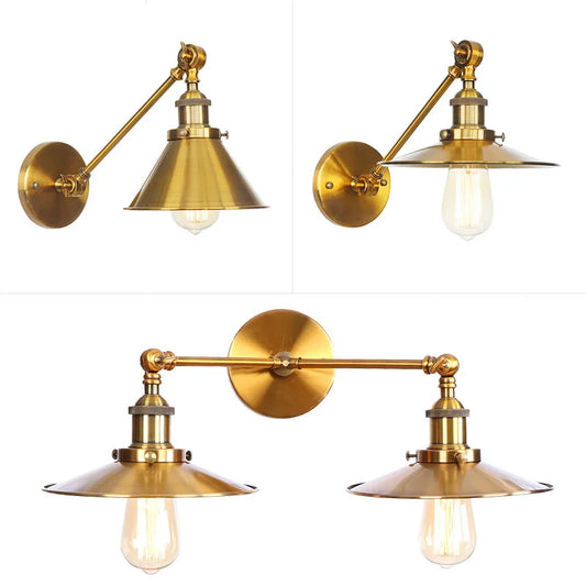 Single brushed gold cone shade wall sconce with adjustable arm in a tilted position