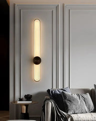 Modern wall sconce on a gray wall with a sofa and side table in the background