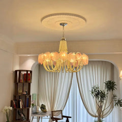 A close-up of a gold chandelier with pink glass elements and pearl bead strands, highlighting its intricate design.