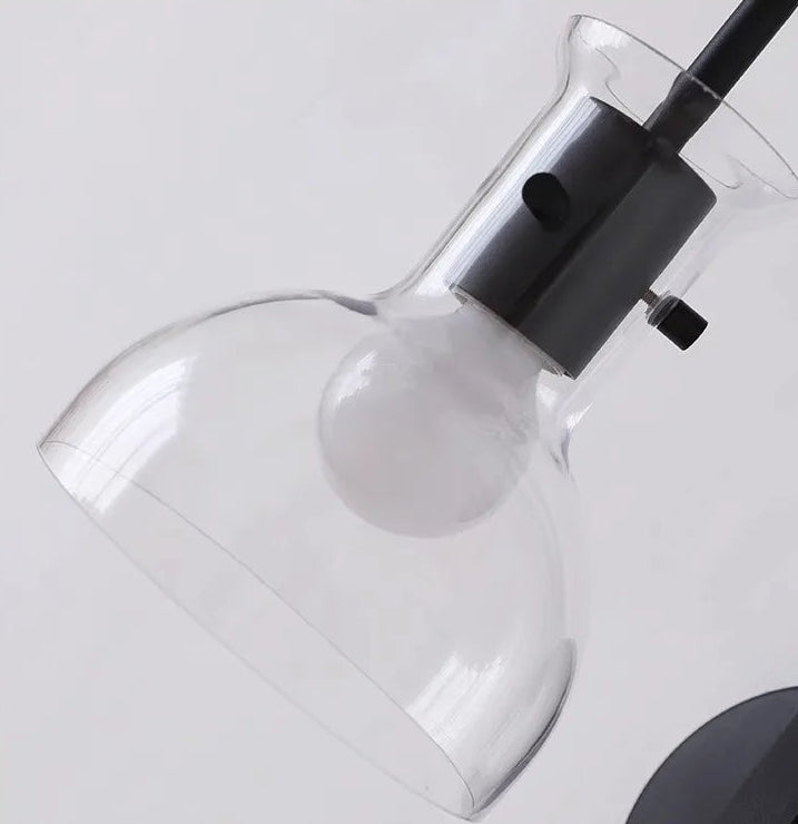 Modern light fixture with clear glass shade and black base on a white background