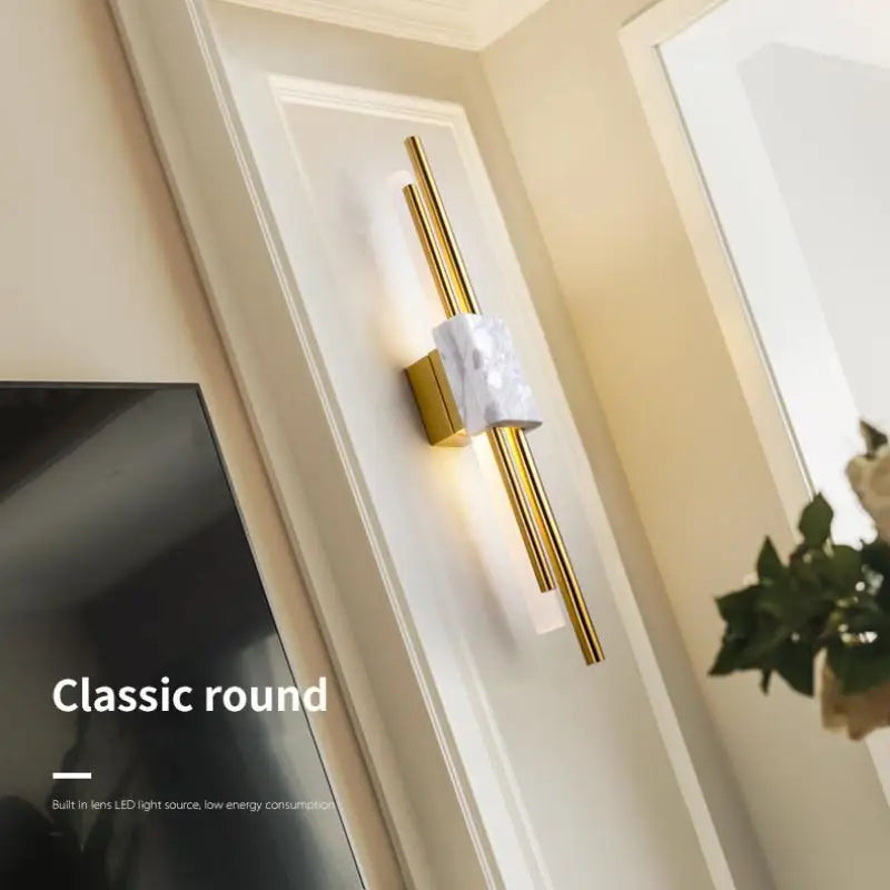 Gold wall sconce with marble accent on a neutral wall.