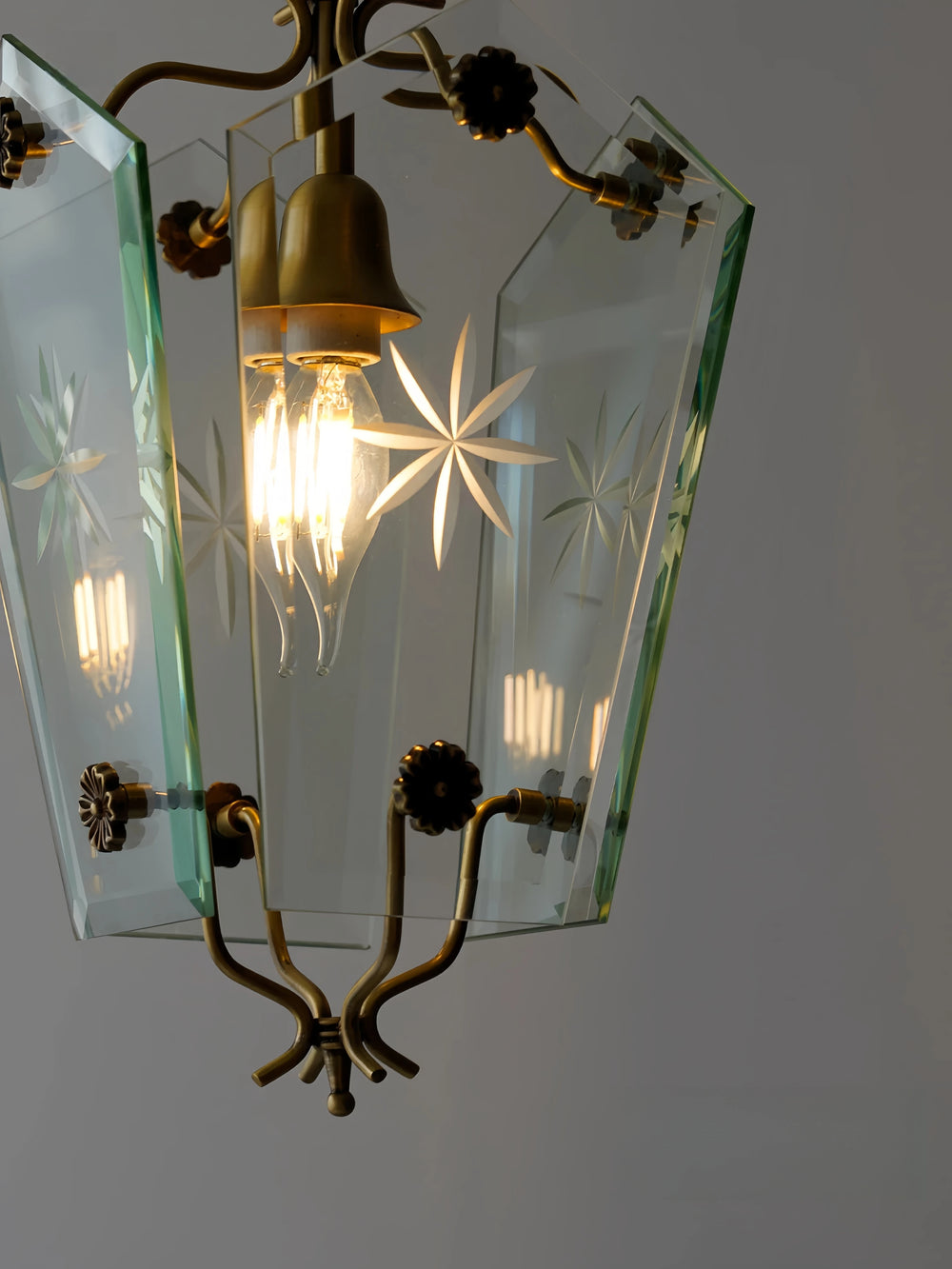 Vintage-style chandelier with brass fixtures and glass shades on a plain background