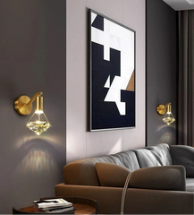 Modern living room with abstract art, gold wall sconces, and a brown sofa.