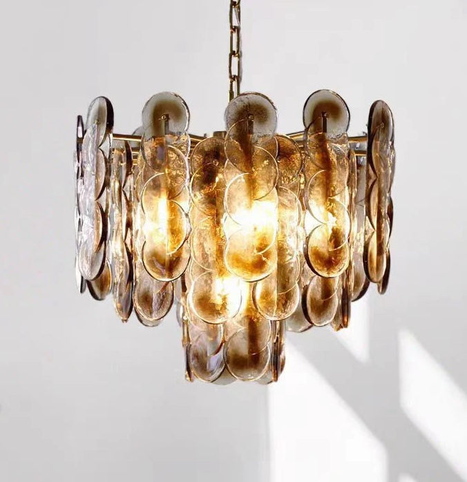 Close-up of a cascading pendant light with multiple amber glass discs and a gold chain.