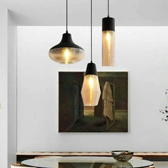 A group of three pendant lights with ribbed glass shades, one featuring a large painting in the background.