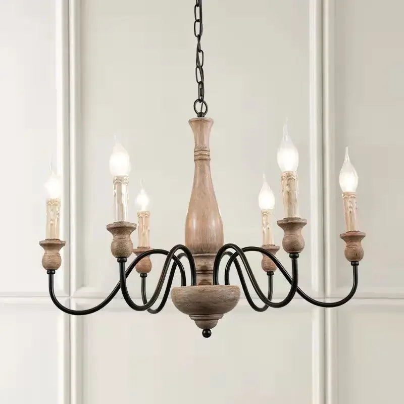 Wooden chandelier with six candle-style lights on a white wall background