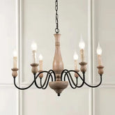 Wooden chandelier with six candle-style lights on a white wall background