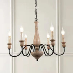 Wooden chandelier with six candle-style lights on a white wall background