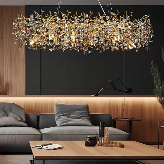 Gold crystal chandelier with a branch-like design and clear faceted crystals hanging above a modern living room sofa.
