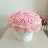 Pink flower arrangement in a decorative vase on a white surface