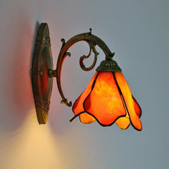 Decorative wall lamp with orange glass shade on a plain background