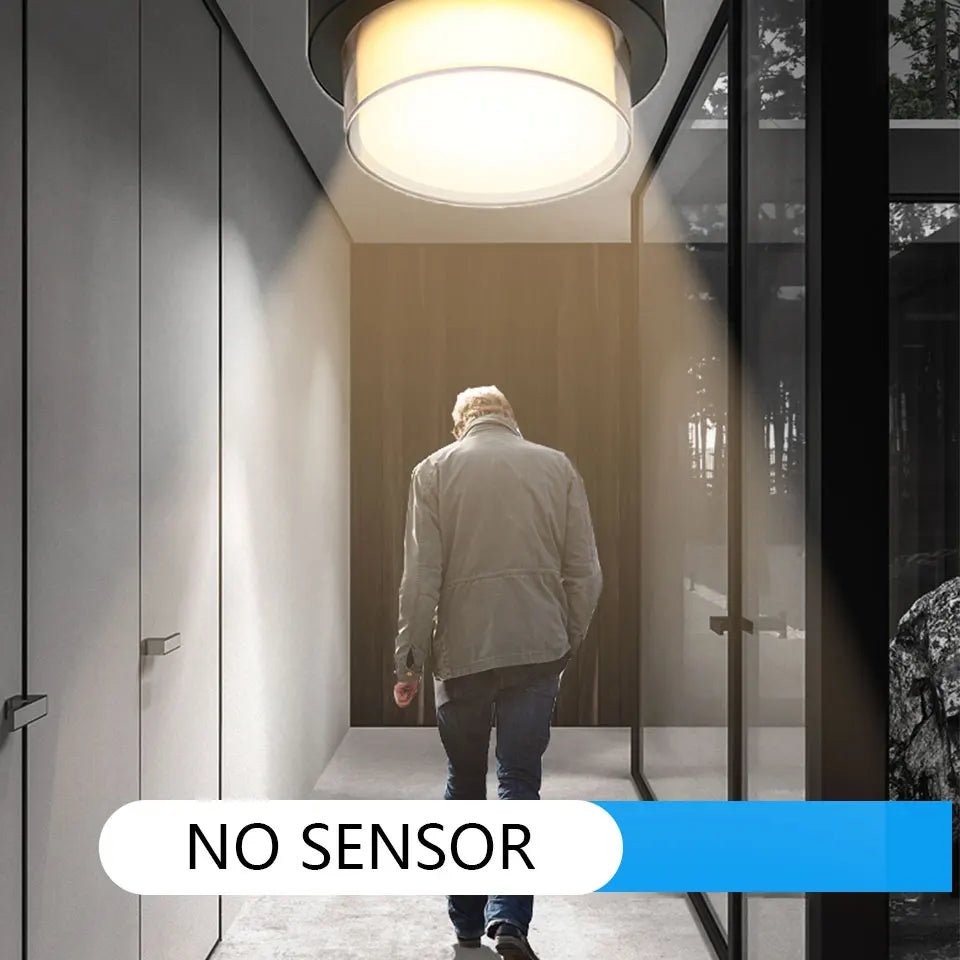 Person walking into a modern home with a light fixture above, labeled 'NO SENSOR'.