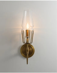 Brass wall sconce with clear glass shade on a light gray background
