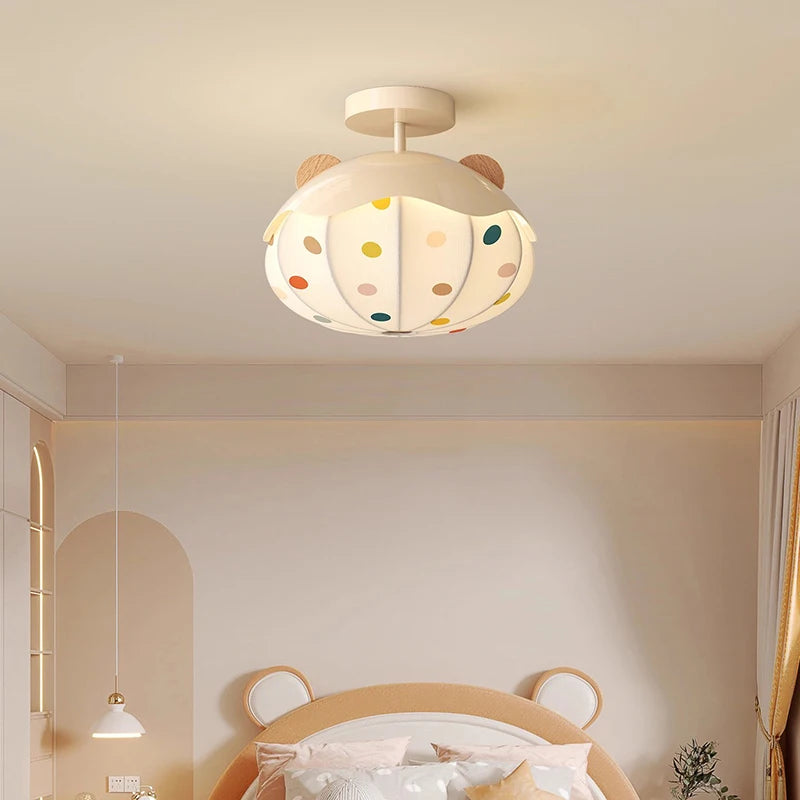 Close-up of a white ceiling light featuring a hot air balloon design with colorful polka dots and wooden accents, attached to a white ceiling.