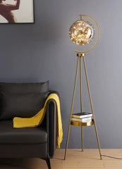 Gold floor lamp with a decorative light shade in a living room setting.