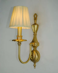 Gold wall sconce with a white lampshade on a plain wall