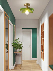 Modern interior hallway with green wall, ceiling light fixture, and wooden furniture.