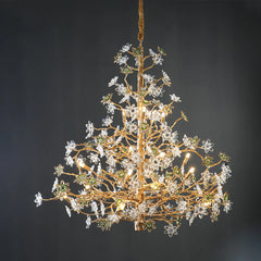 A detailed shot of a gold branch chandelier with clear and green crystal flowers, isolated against a dark gray background.
