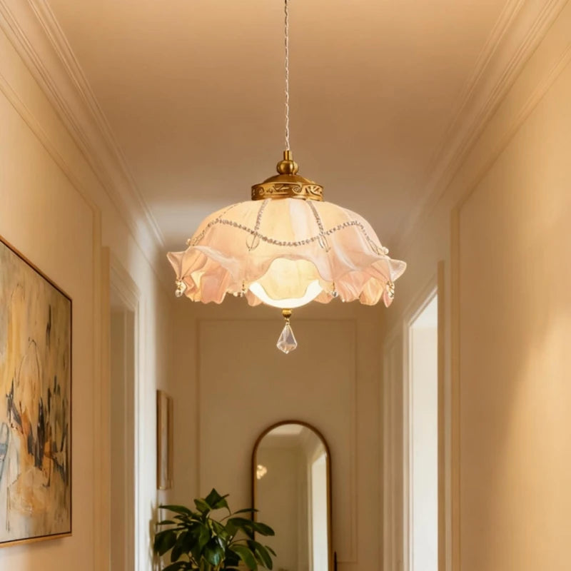 A gold floral pendant light with crystal accents hanging in a hallway.