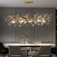 Gold leaf crystal chandelier with a branch-like design hanging over a dining table.
