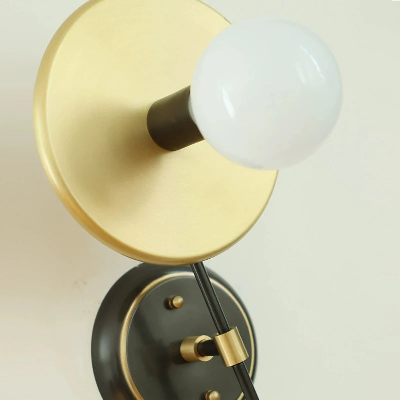 Wall-mounted light fixture with gold and black design on a neutral background