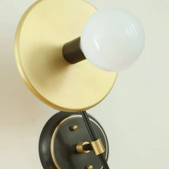 Wall-mounted light fixture with gold and black design on a neutral background