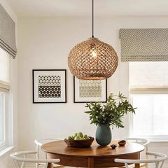 A single woven bamboo pendant light with a spherical shape hanging above a wooden dining table with chairs.