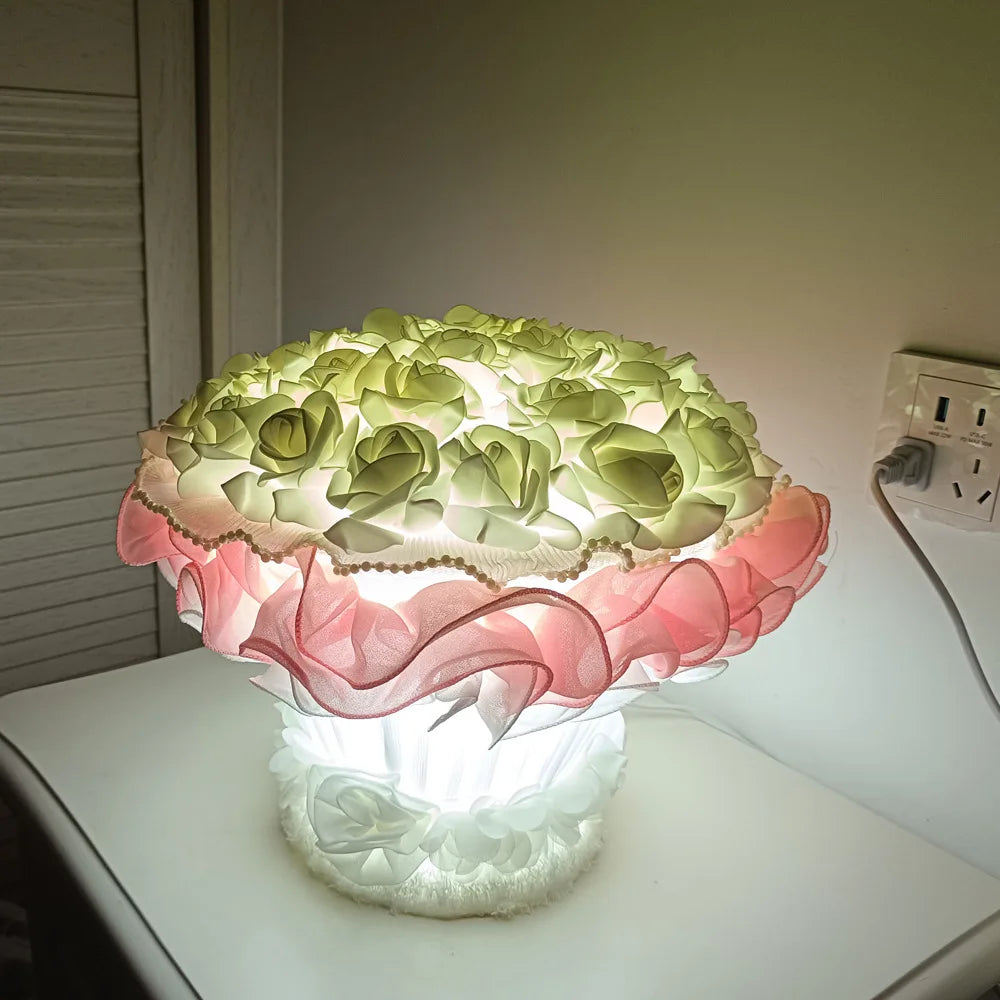Decorative lamp with floral design on a table next to an electrical outlet.