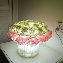 Decorative lamp with floral design on a table next to an electrical outlet.