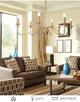 Gold candelabra-style chandelier with curved arms, illuminating a living room space.