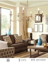Gold candelabra-style chandelier with curved arms, illuminating a living room space.