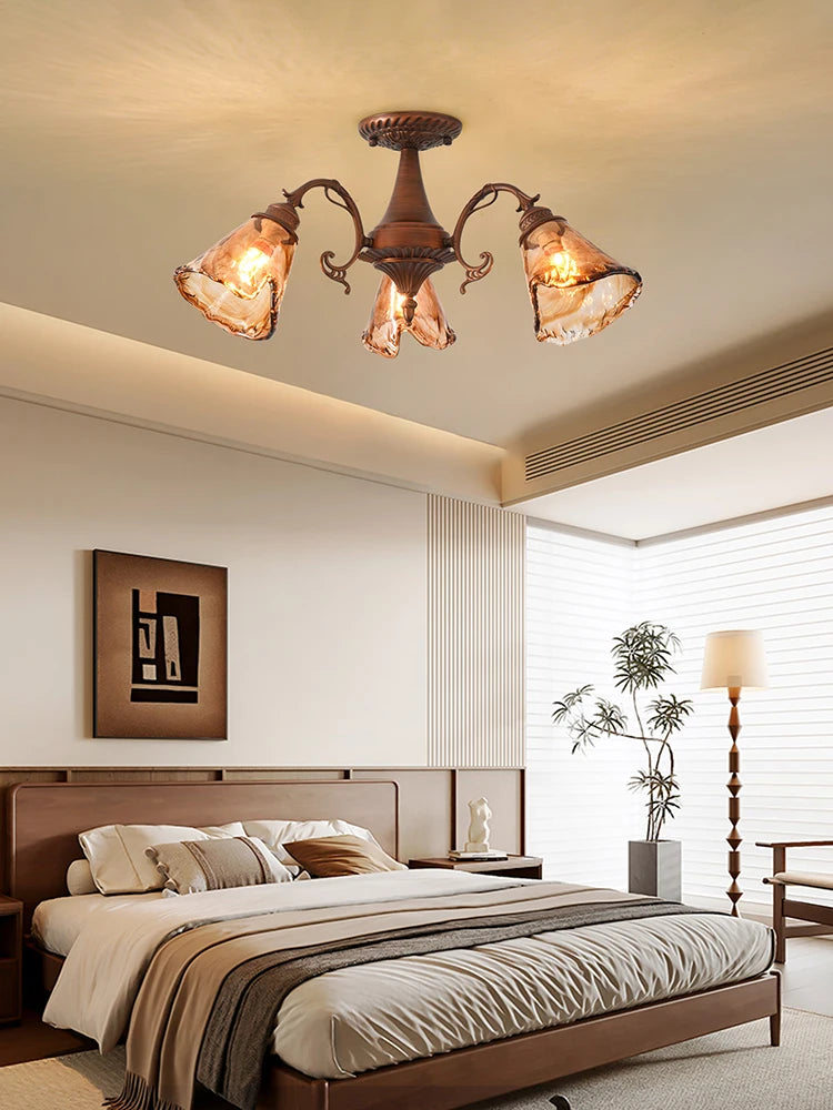 The illuminated brushed bronze floral semi-flush mount ceiling light casting a warm glow on the ceiling and the room above a bed.
