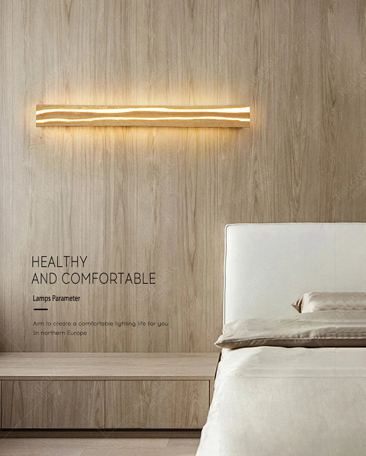Modern wall light fixture on a wooden wall above a bed in a bedroom setting.