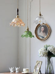 Three pendant lights with floral designs hanging above a table with decorative items.
