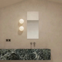 Modern bathroom with a marble countertop, wall-mounted mirror, and round lights.