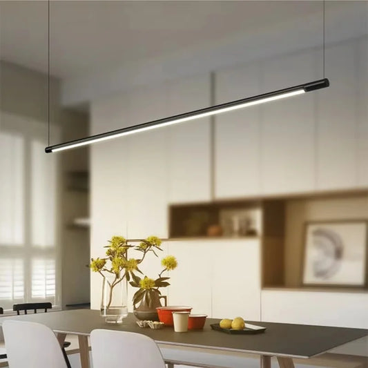 Black minimalist linear pendant light hanging above a dining table with yellow flowers