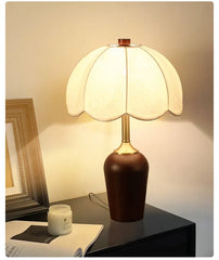Decorative table lamp with a brown base and white shade on a dark surface.