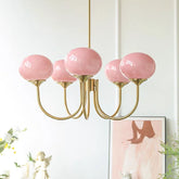 A close-up shot of a gold chandelier with five pink globe-shaped glass shades.