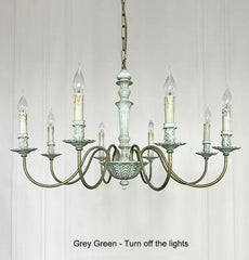 Vintage-style chandelier with glass shades on a white paneled wall.