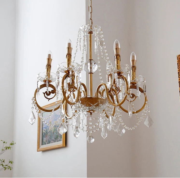 Gold chandelier with crystal accents on a white wall background