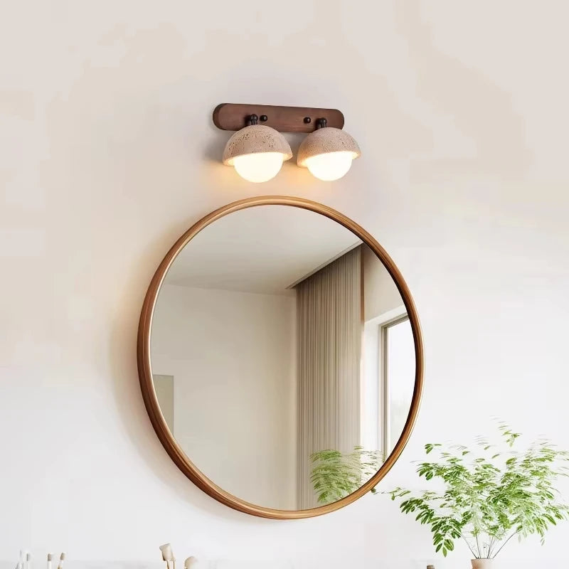 Round mirror with wooden frame on a wall with a light fixture above