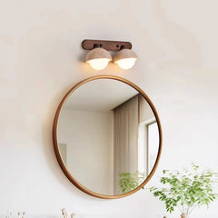 Round mirror with wooden frame on a wall with a light fixture above