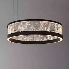 Close-up of a black ring-shaped pendant light with a textured glass diffuser, illuminated from within, against a dark background.