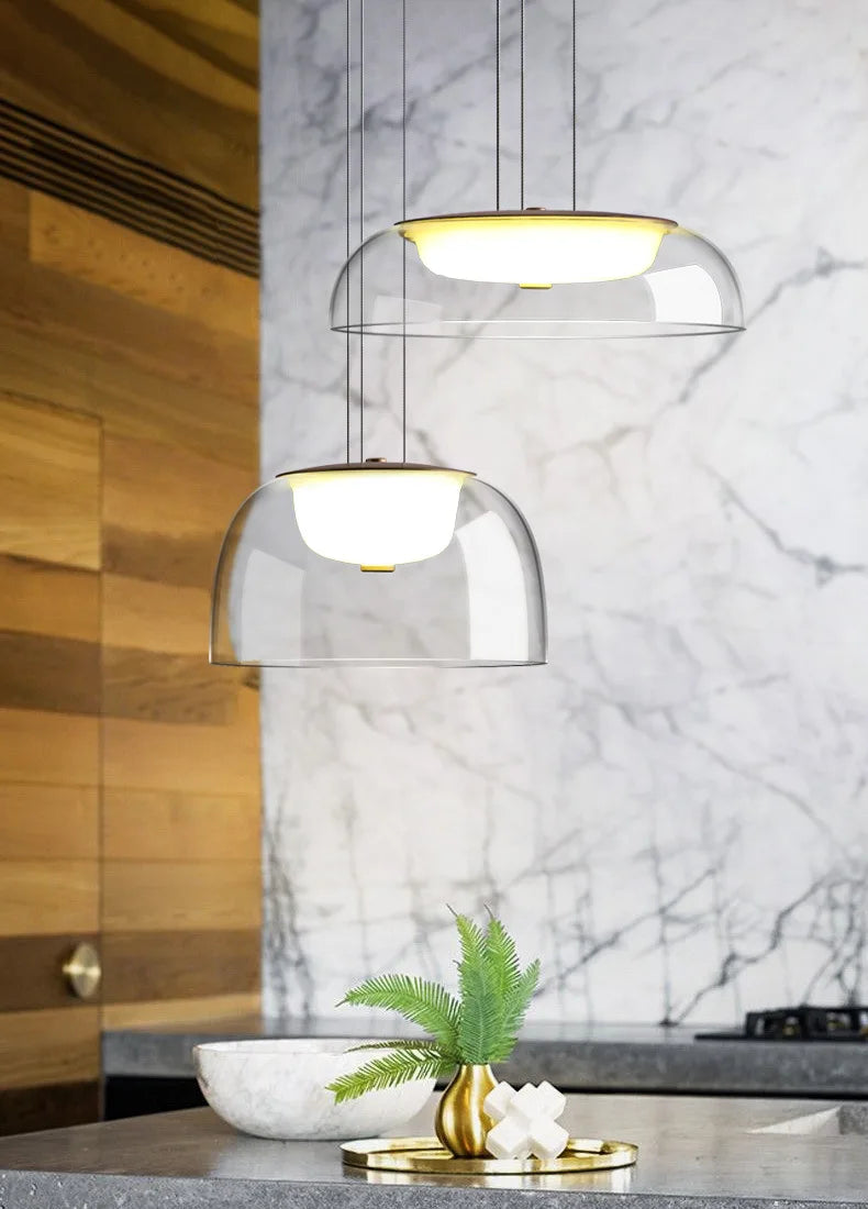 Modern pendant lights hanging above a kitchen counter with marble backsplash.