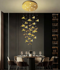 Modern chandelier hanging above a dining table in a stylish room with dark walls and shelves.