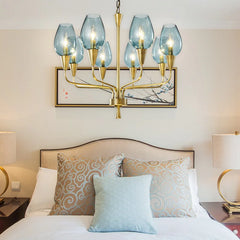 Gold chandelier with blue glass shades hanging above a bed in a bedroom.