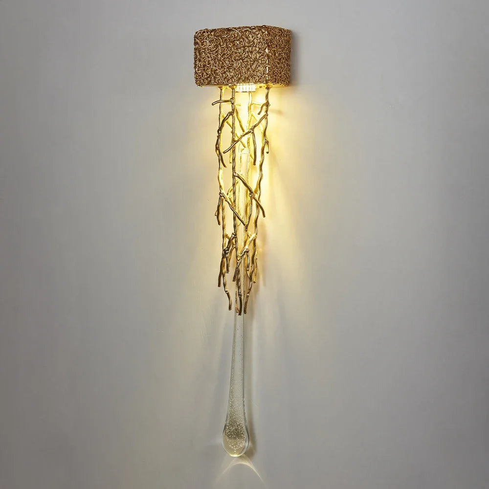 Decorative wall light with a textured gold top and glass body on a gray background